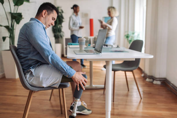 istock Inclusive workplace: professional with prosthetic leg at desk 2153889753