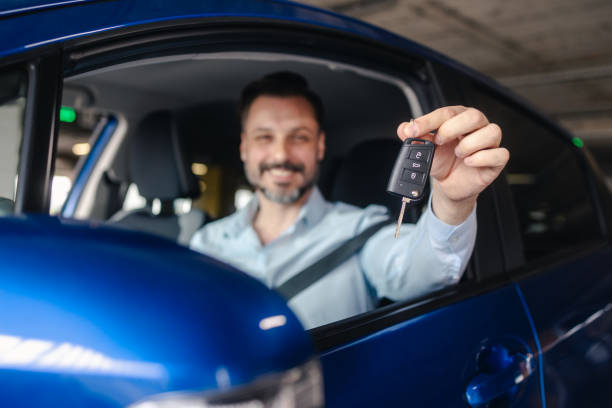 istock Smiling handsome man holding car key and sitting inside a car 2153889756