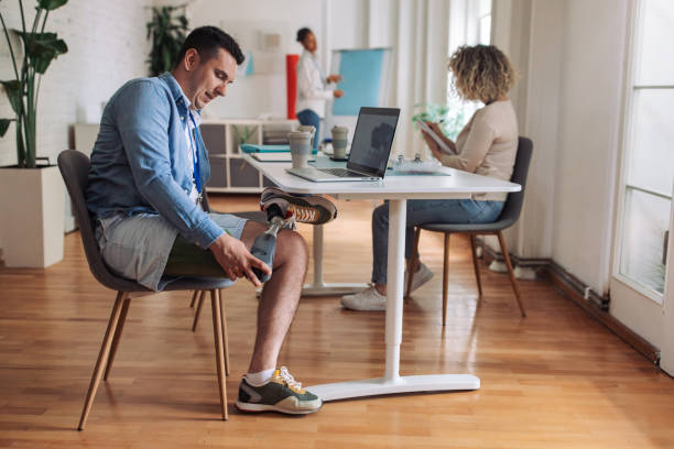 istock Diverse workplace environment with an individual showcasing a prosthetic limb, working comfortably at an adaptive office desk 2153889934