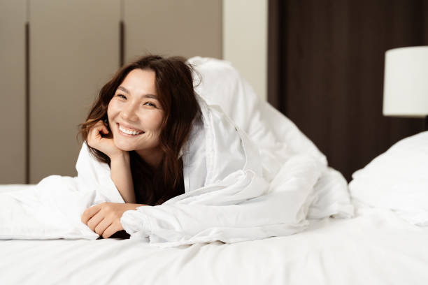 istock Happy Young Woman Relaxing In Bed With White Sheets 2153901679