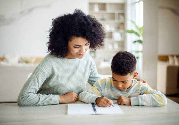 istock A young mother helps her son with his homework. 2153903533