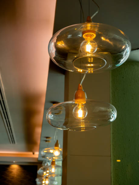 istock Beautiful retro luxury light lamp hanging from ceiling in restaurant or cafe. Vertical photography of glass bowl modern luxury design pendant lamp with light bulbs decoration in bright room. 2153905971