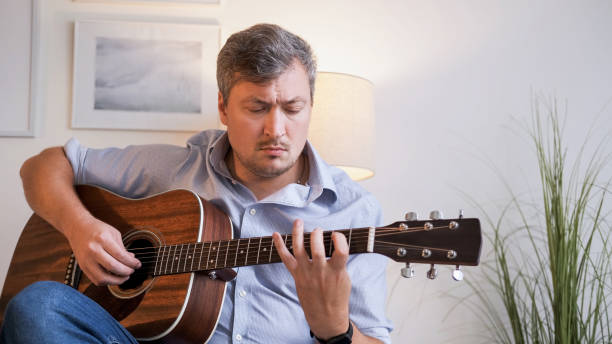 istock Music practicing man playing acoustic guitar home 2153906692