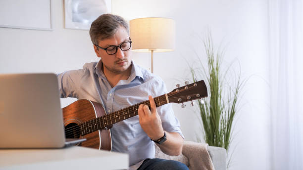 istock Guitar practicing video conference man laptop home 2153906696