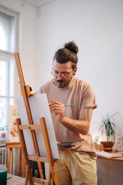 istock A focused trendy painter painting on easel at creative art studio. 2153906971