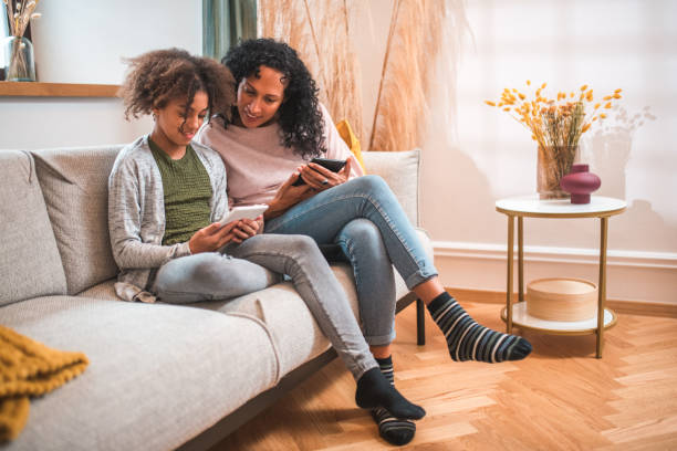 istock Hispanic Mother and Mixed Race Daughter Immersed in E-Readers 2153908794
