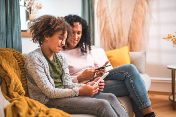 istock Hispanic Mother and Mixed Race Daughter Engrossed in E-Books 2153908795