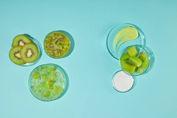 istock Unique template for advertising shot from above on blue texture, round glassware items containing sliced and chopped kiwi, white and yellow exfoliation scrubs. Displaying and copy space 2153910033