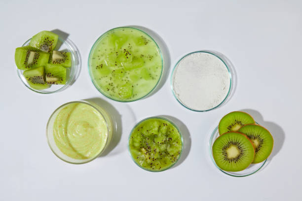 istock White table containing plenty glassware with fresh kiwi and organic exfoliation cream has kiwi origin. Creative photo from top view with blank space for adding text or elements of design 2153910118