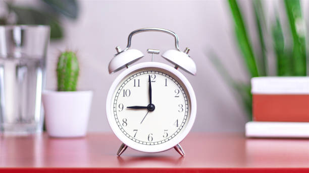 istock Classic white clock on a table. The clock hand points to 9:00 or 21:00, close up photo 2153910440