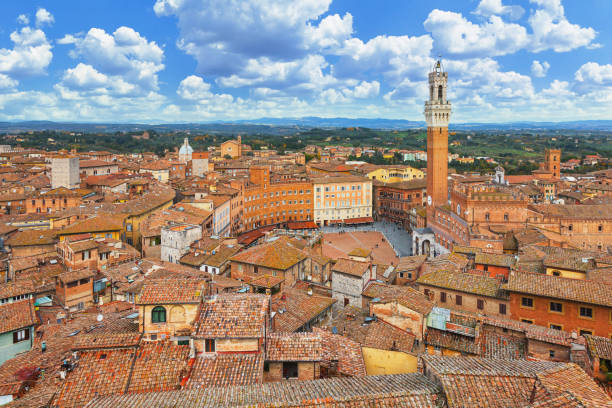 Panoramic view of the old city of Siena with the Torre del Mangia, Piazza del Campo and Palazzo Pubblico - Tuscany, Italy A panoramic view of the old city of Siena in Tuscany, Italy, showcases the historic Piazza del Campo and the majestic Palazzo Pubblico. The city's medieval architecture, with its warm terracotta hues and narrow winding streets, is beautifully framed by the surrounding Tuscan landscape. The Piazza del Campo, renowned for its unique shell shape and the famous Palio horse race, sits at the heart of Siena, while the Palazzo Pubblico, with its iconic Torre del Mangia tower, stands as a testament to the city's rich history and cultural heritage. torre del mangia stock pictures, royalty-free photos & images