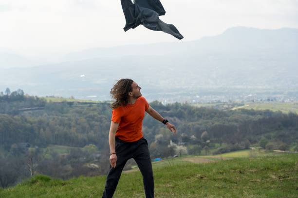 istock Young man throwing a jacket in the air on mountain 2153928763