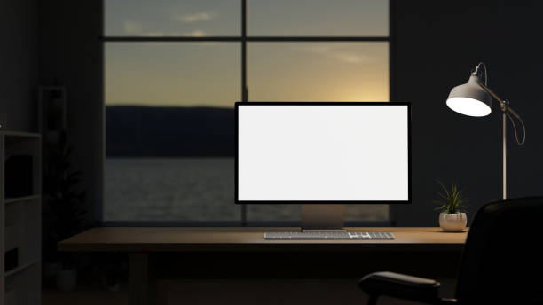 istock A modern office with a computer mockup and a dim light from a lamp on a table against the window. 2153929273