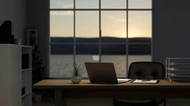 A modern private office room at sunset, a laptop computer on a table near the window.
