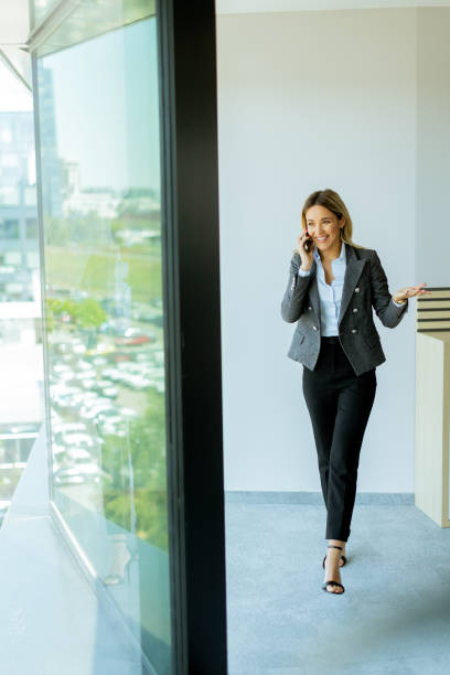 istock Young professional woman talking on mobile phone by office window on a sunny day 2153929538