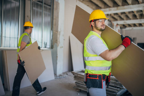 istock Two construction workers in safety gear efficiently transport drywall sheets at a construction site 2153929648