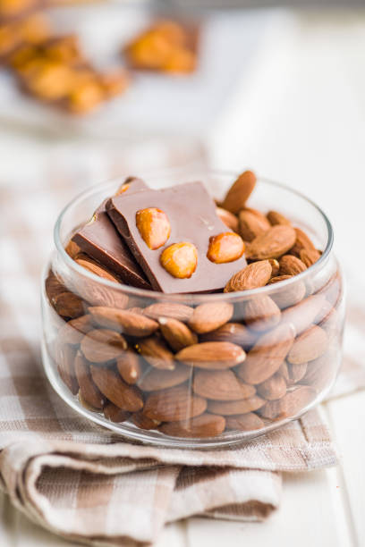 istock Broken chocolate bar with almonds in bowl on kitchen table. 2153930115