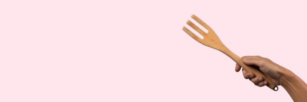 istock Hand holding wooden fork on pink background, cutout 2153932213