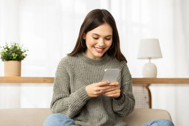 istock Positive young woman using smartphone at home 2153933340