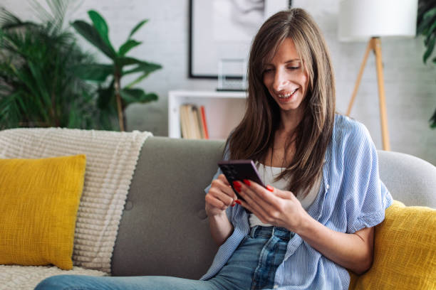 istock Connected and Content. Woman Enjoys Leisure Time on Sofa with Smartphone 2153935330
