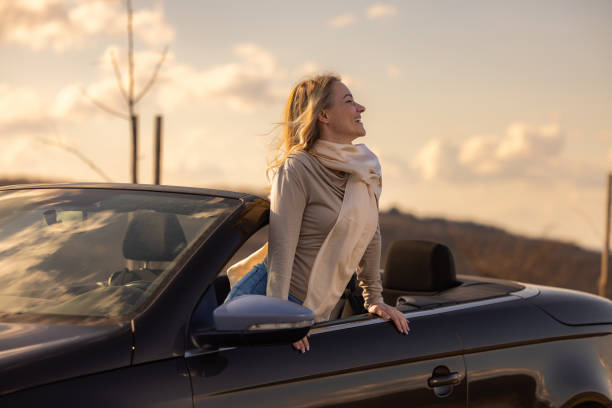 istock Woman enjoys in convertible during sunset 2153935647