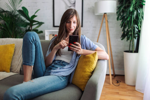 istock Connected and Content. Woman Enjoys Leisure Time on Sofa with Smartphone 2153936262