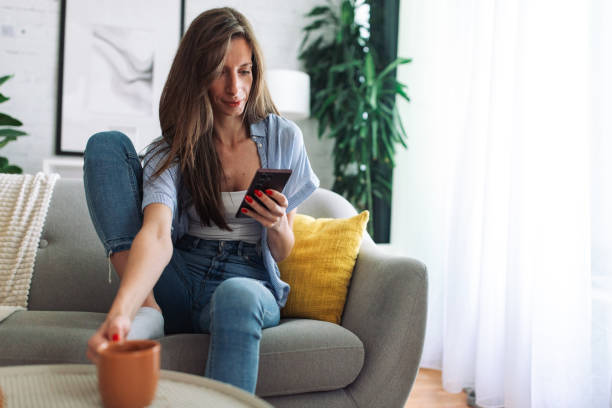 istock Connected and Content. Woman Enjoys Leisure Time on Sofa with Smartphone 2153936308