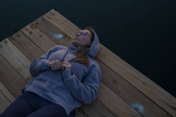 Woman lying down on the pier at lake, closeup portrait, summer sunset