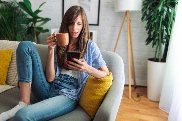 istock Connected and Content. Woman Enjoys Leisure Time on Sofa with Smartphone 2153937261