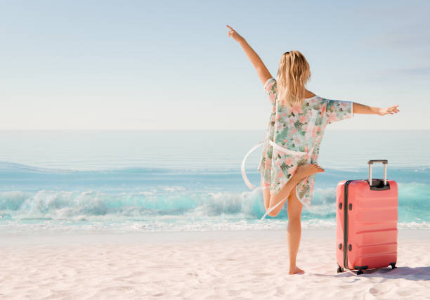 istock Woman with suitcase enjoying tropical beach with ocean waves 2153939501