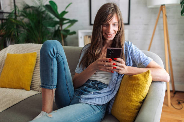 istock Connected and Content. Woman Enjoys Leisure Time on Sofa with Smartphone 2153939562