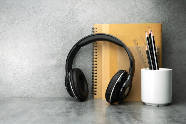 Headphones and notebook and pencil cup on table. Work desk space