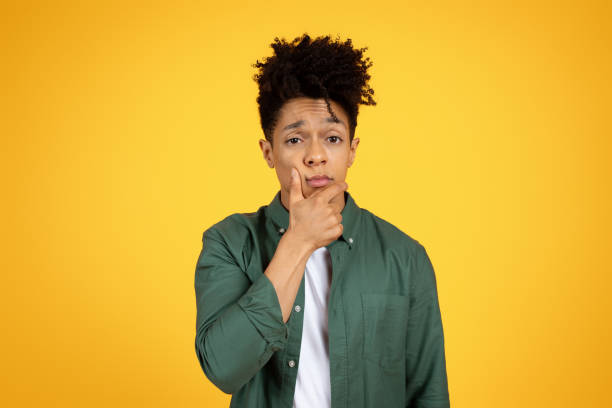 istock Doubtful african american guy touching face and looking at camera 2153942183