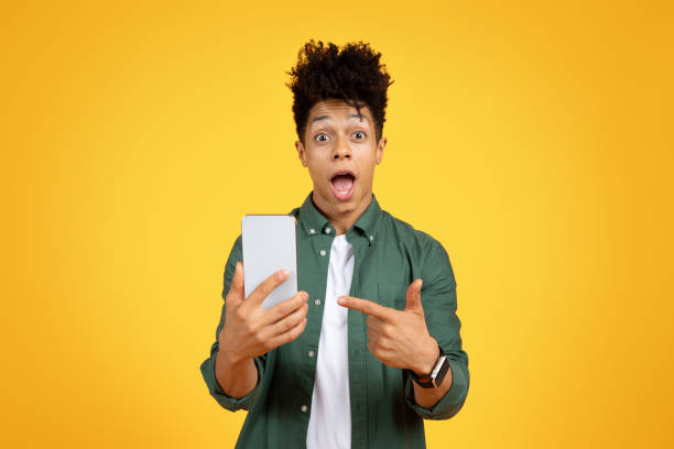 istock Amazed african american guy pointing at smartphone in his hand 2153942298