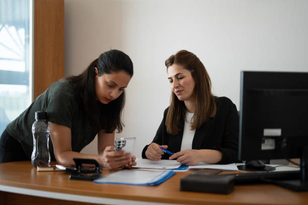 istock Two Businesswomen looking at smartphone in office 2153942342