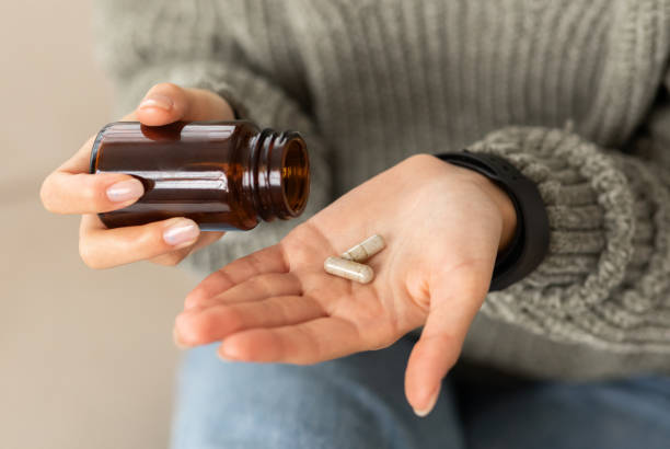 hands young woman holding medicine herbs capsules Closeup hands of young woman holding medicine herbs capsules, cropped of lady taking supplement product or vitamin type capsule. Nutrition for women, healthcare, drugs nutritional supplement stock pictures, royalty-free photos & images