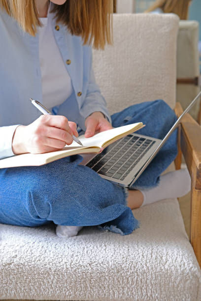 istock A girl leads a glider while working, takes notes in a notepad. A young woman is studying or working remotely at home sitting on an armchair. Work from home office. The student uses distance learning on the computer and on the Internet. 2153945507