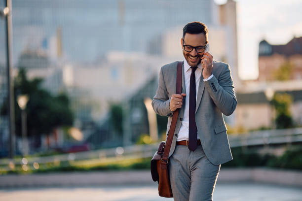 istock Happy businessman making a phone call while walking on the street. 2153946884