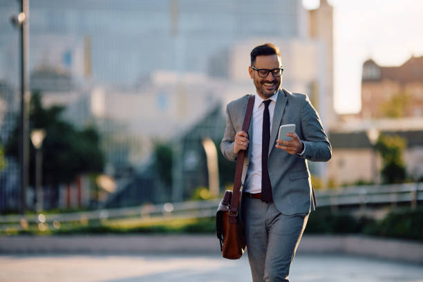 istock Happy businessman texting on smart phone while walking in the city. 2153946895