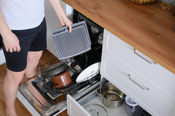 istock Man taking clean dishes out of dishwasher 2153956768