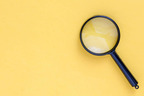 istock close up magnifier glass on yellow background 2153957159