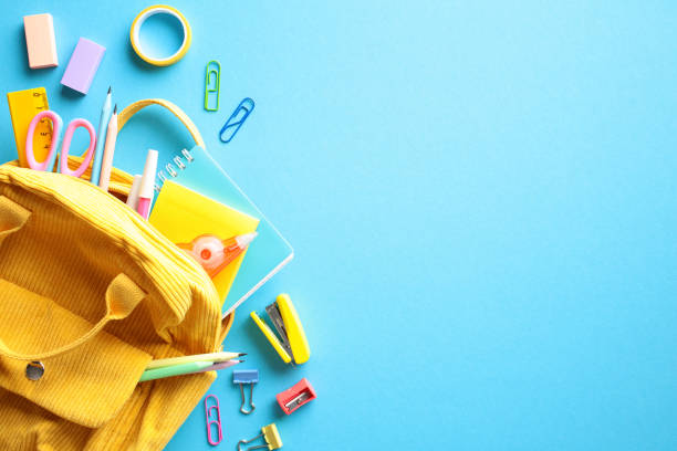 istock Back to School concept. Unleash creativity and productivity with this vibrant collection of school supplies. A yellow backpack spills a rainbow of pencils, erasers, clips, and notebooks onto a blue 2153957426