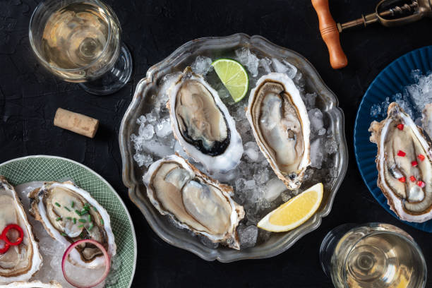 istock Oysters on ice, with various toppings and white wine, shot from the top 2153958319