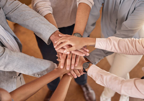 istock Business people, hands and teamwork in collaboration above for meeting trust, unity and community at office. Top view of group piling hand together for celebration, success or workplace team building 2153959395