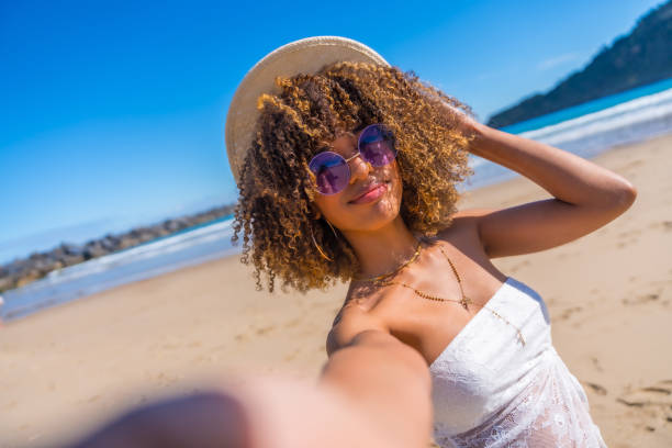 istock Cute latin woman taking selfie on the beach 2153960251