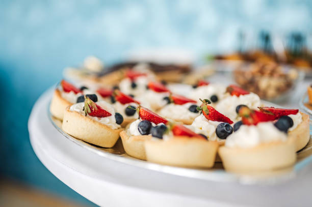Strawberry tarts with cream and blueberries. Finger food for a party.