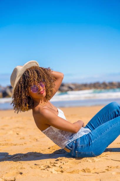 istock Sensual woman with sun hat sitting at beach smiling 2153960537