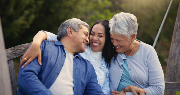 happy family, senior parents or woman on bench in nature, hug or bonding in smile on retirement. mature man, mother and older daughter for together in laughter, lounge and embrace for love in garden - filhos adultos imagens e fotografias de stock