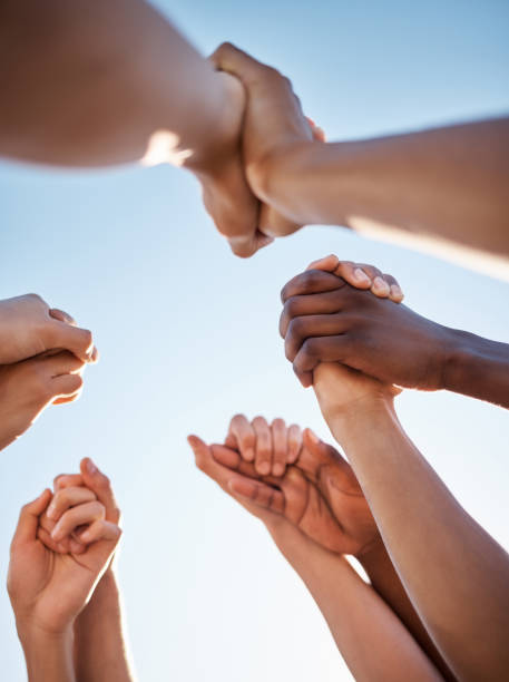 istock Low angle, group and holding hands in support, trust huddle and motivation for global success, volunteer community or diversity. People, friends or teamwork collaboration in circle for climate change 2153967151