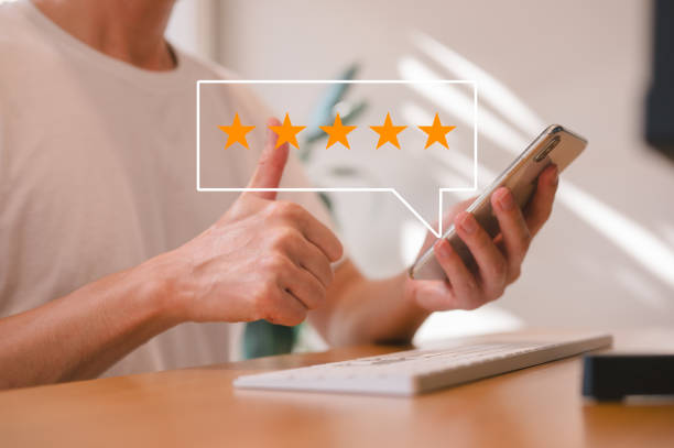 istock feedback and Customer service satisfaction survey concept, customer man hand pressing on smartphone screen with gold five star rating feedback icon 2153967532
